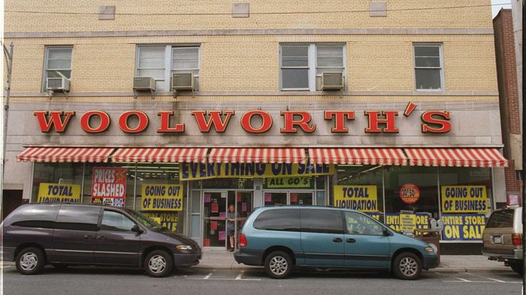 two cars parked in front of a woolworth's store