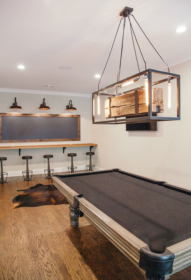 a pool table in the middle of a room with lights hanging from it's ceiling