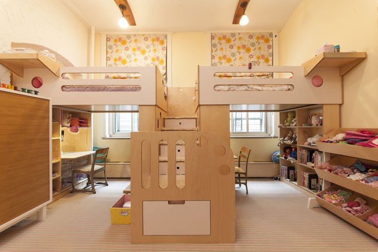 a room with bunk beds, desks and shelves full of toys on the floor