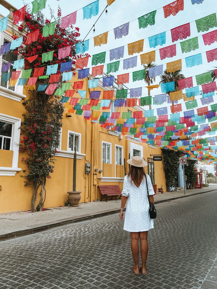 a woman walking down the street in front of some colorful paper decorations hanging above her head