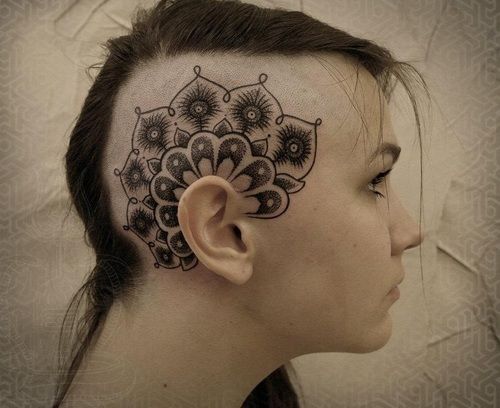 a woman's head with an intricate tattoo design on her forehead and behind the ear