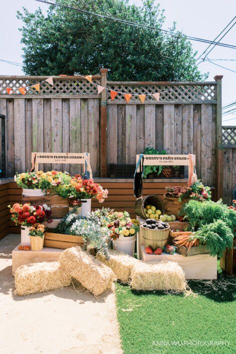 an outdoor vegetable garden with lots of plants and flowers on the ground in front of a wooden fence