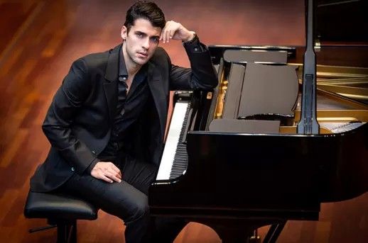 a man in a suit sitting at a piano