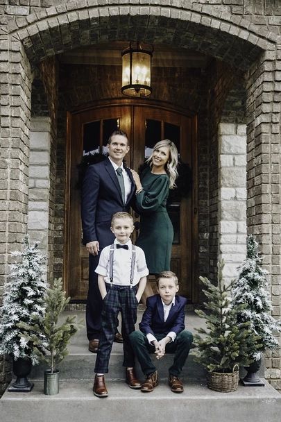 a family posing for a photo in front of a house with christmas decorations on the steps