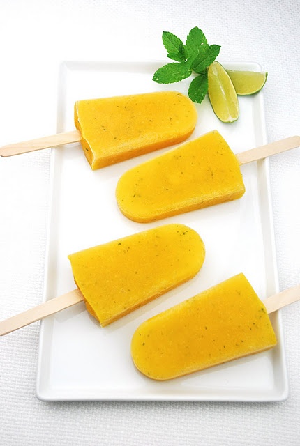 three popsicles on a white plate with limes