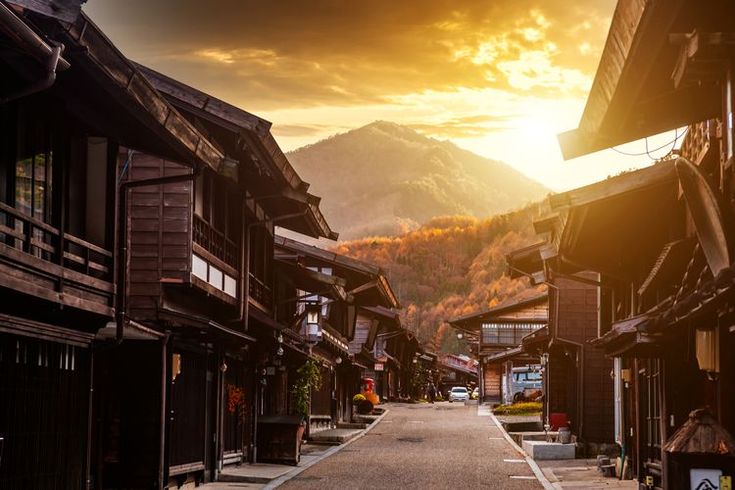 the sun is setting on an old town with mountains in the backgrouds