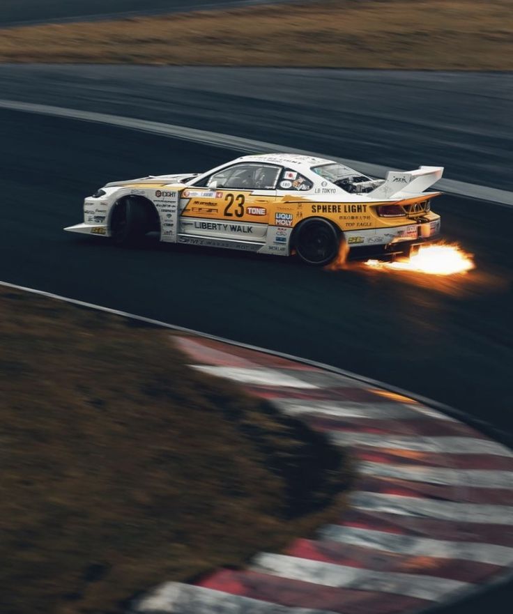 a car with flames coming out of it's tires driving on a race track