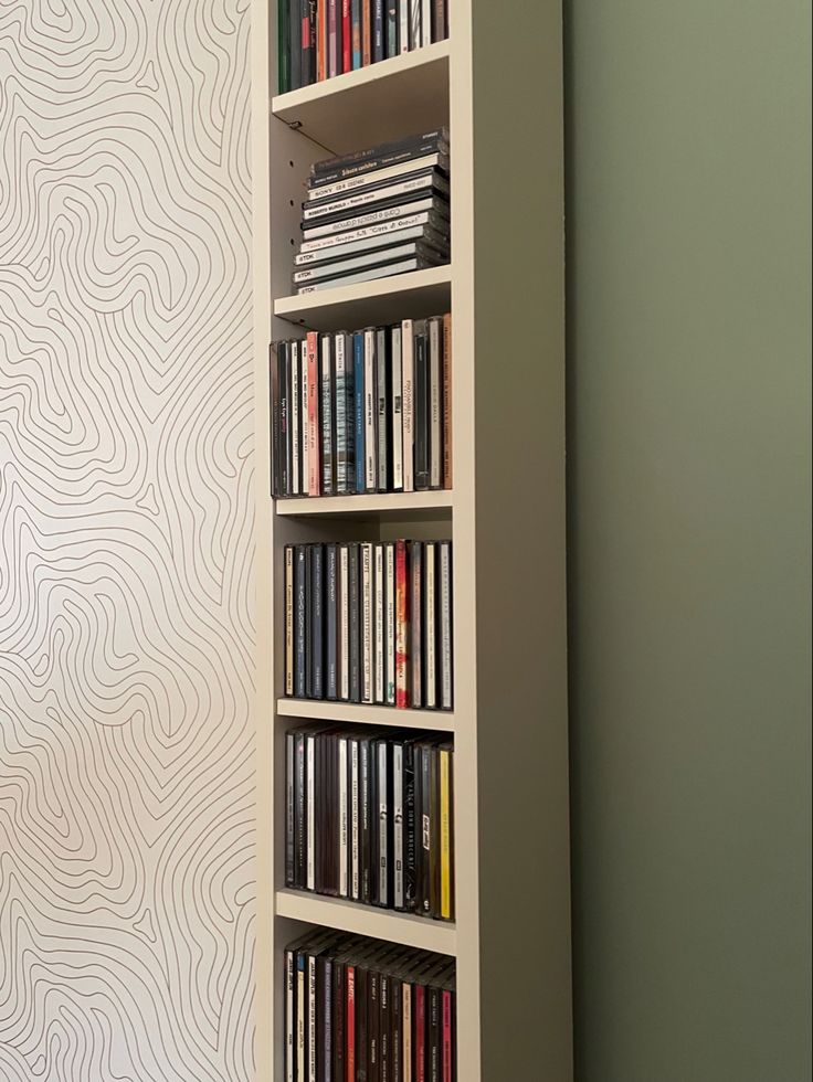 a book shelf filled with lots of books next to a wall mounted clock on the side of a wall