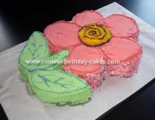 a birthday cake decorated with pink and green flowers on a white paper towel next to a black table