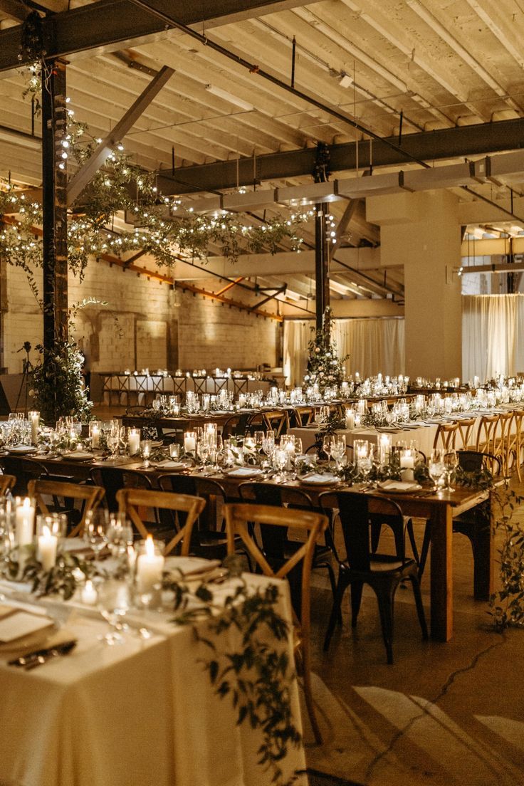 an image of a table setting with candles and greenery on the tables in front of it