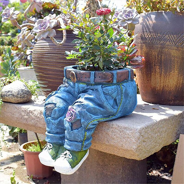 a pair of blue jean pants sitting on top of a cement bench next to potted plants