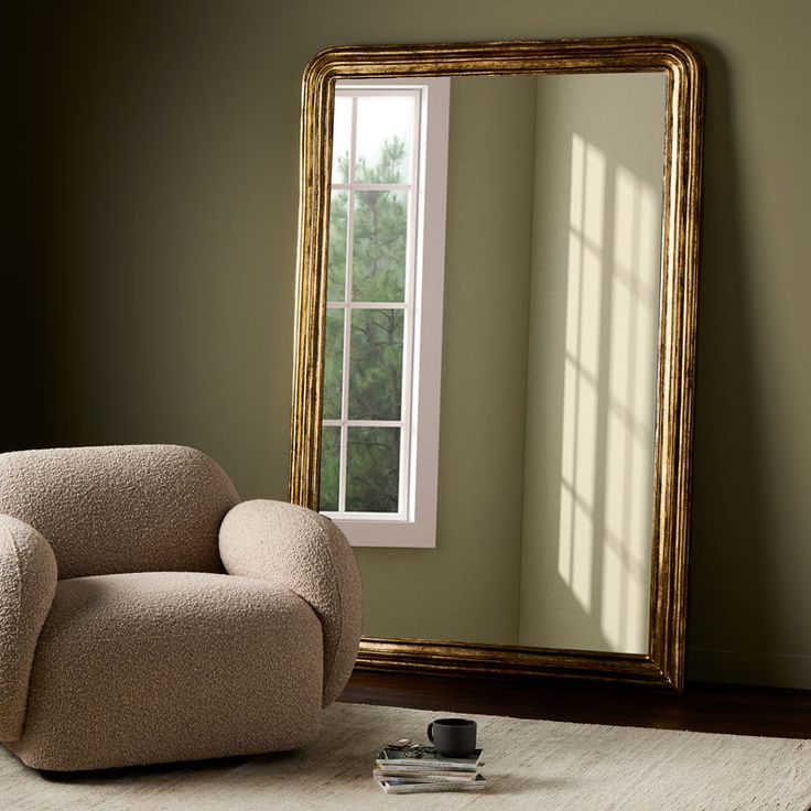 a chair sitting in front of a mirror next to a window and a book on the floor