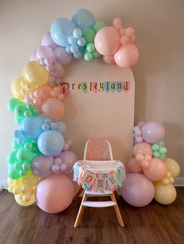 a baby's first birthday party with balloons on the wall and a high chair