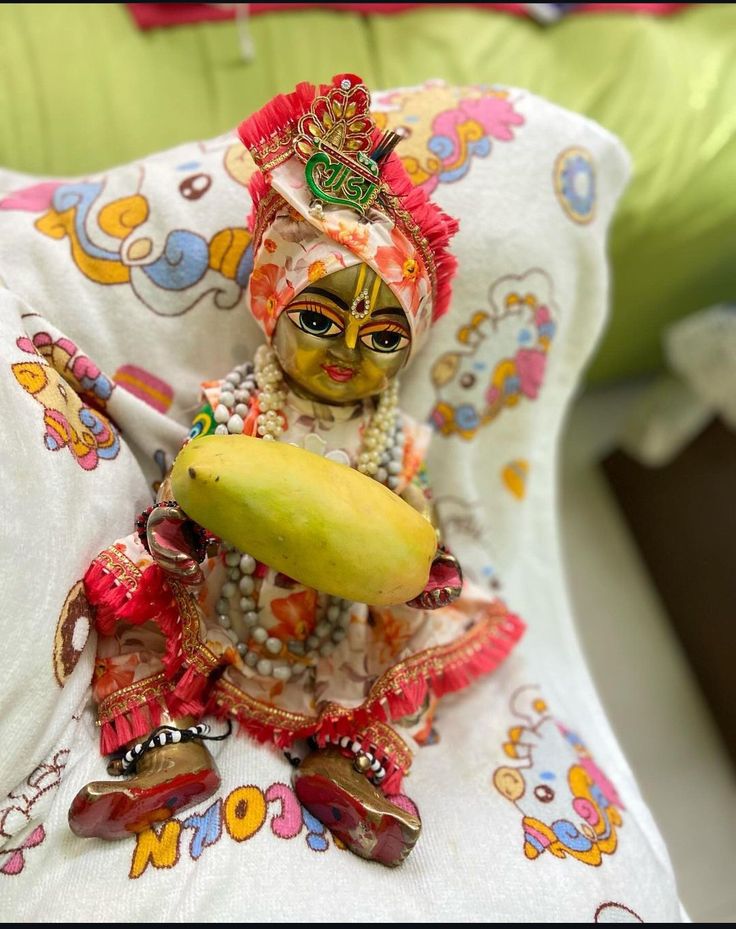 a small figurine sitting on top of a bed next to a yellow banana