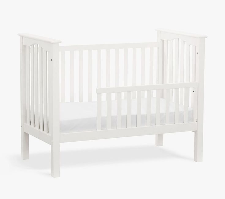 a small white crib with no mattress on it's side, against a white background