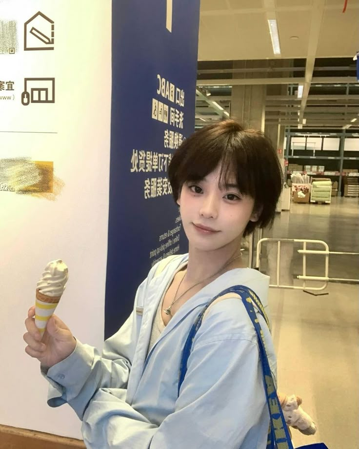 a young woman holding an ice cream cone in her right hand and looking at the camera