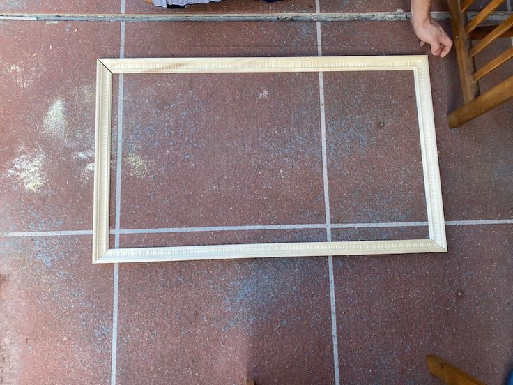 a wooden frame sitting on the floor next to a child's feet and chair