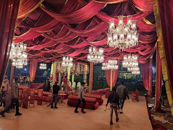 people are standing in the middle of a room with red drapes and chandeliers