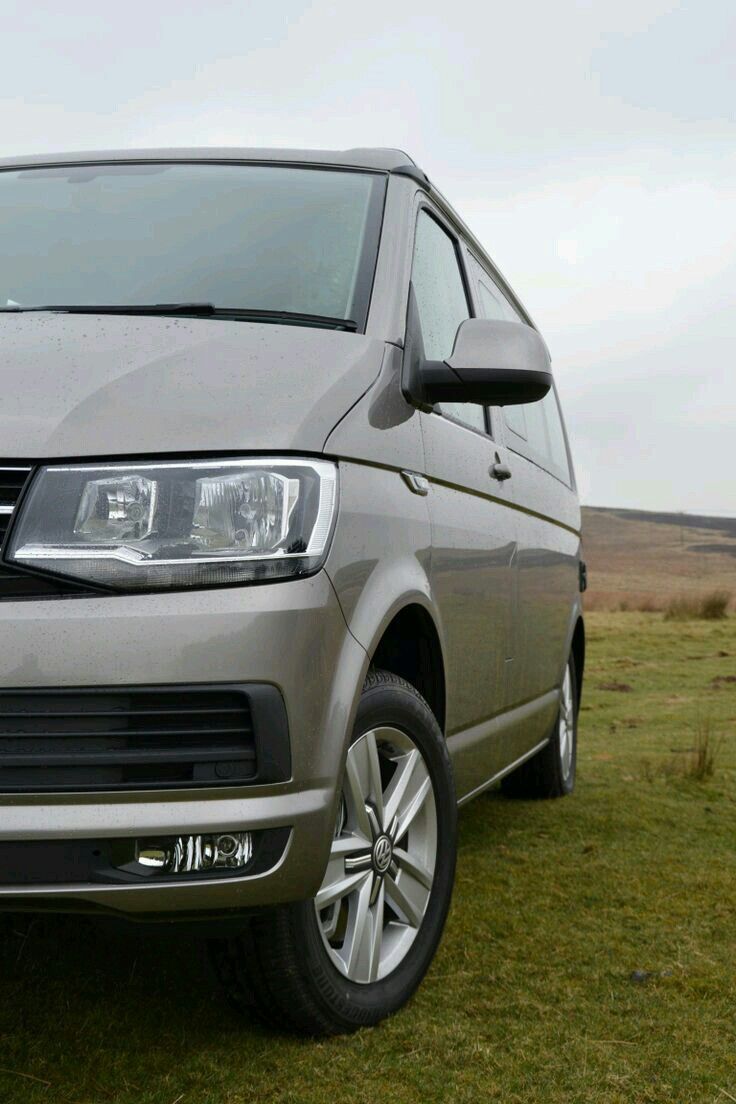 a silver van parked on top of a lush green field