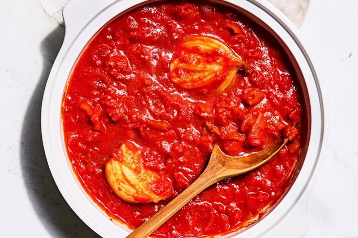 a white bowl filled with red sauce and two wooden spoons