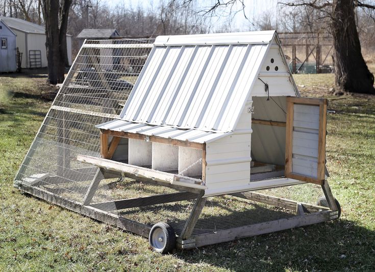 a small chicken coop on wheels in the grass