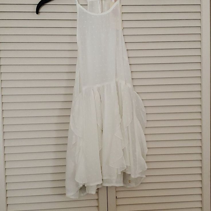 a white dress hanging on a wall next to a door with a hanger in front of it