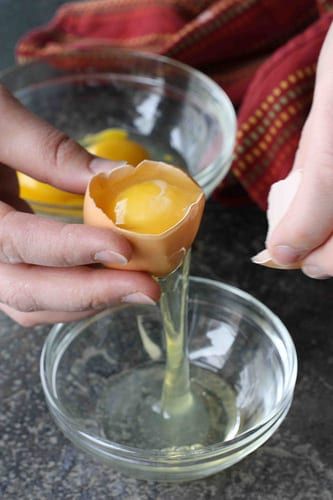 someone is squeezing an egg into a glass bowl