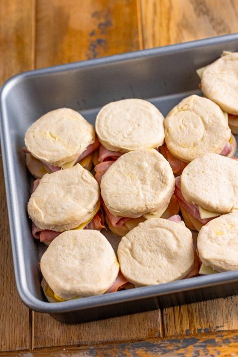 a metal pan filled with mini sandwiches on top of a wooden table