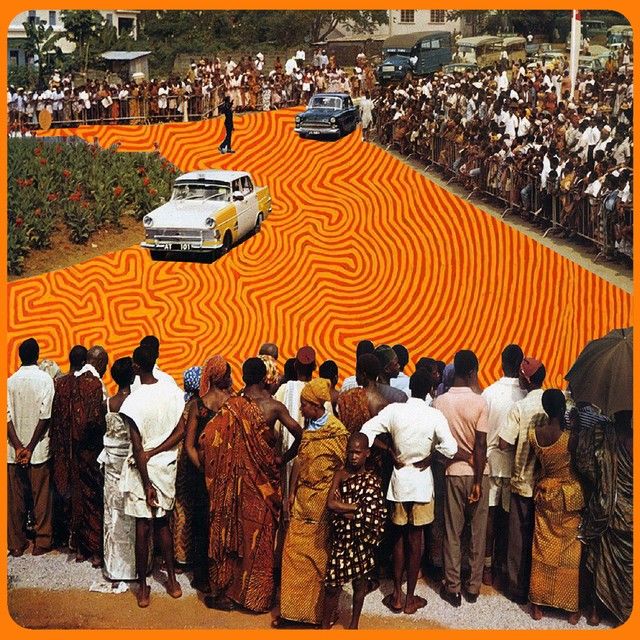 a group of people standing in front of an orange maze with a car driving through it