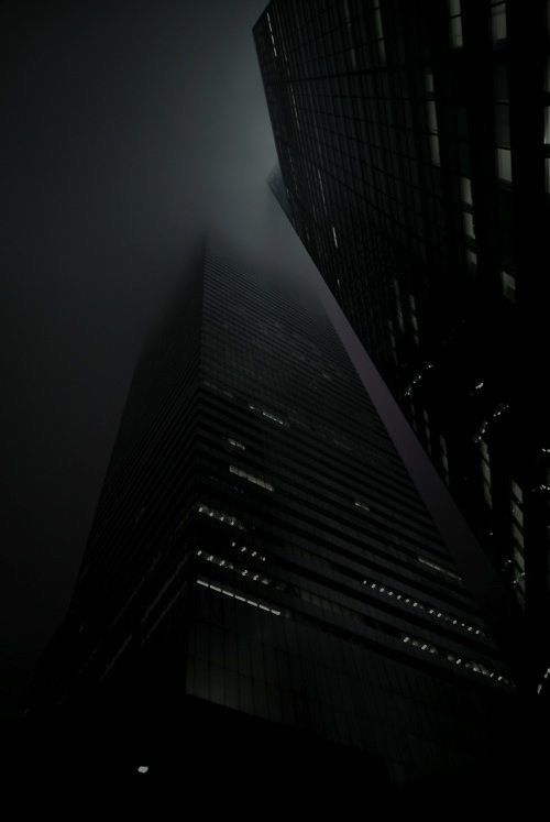 the top of a tall building in the foggy night with lights shining on it