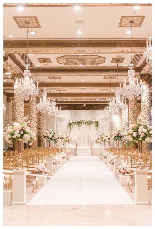 a wedding ceremony setup with chandeliers and white flowers on the aisle in an elegant ballroom