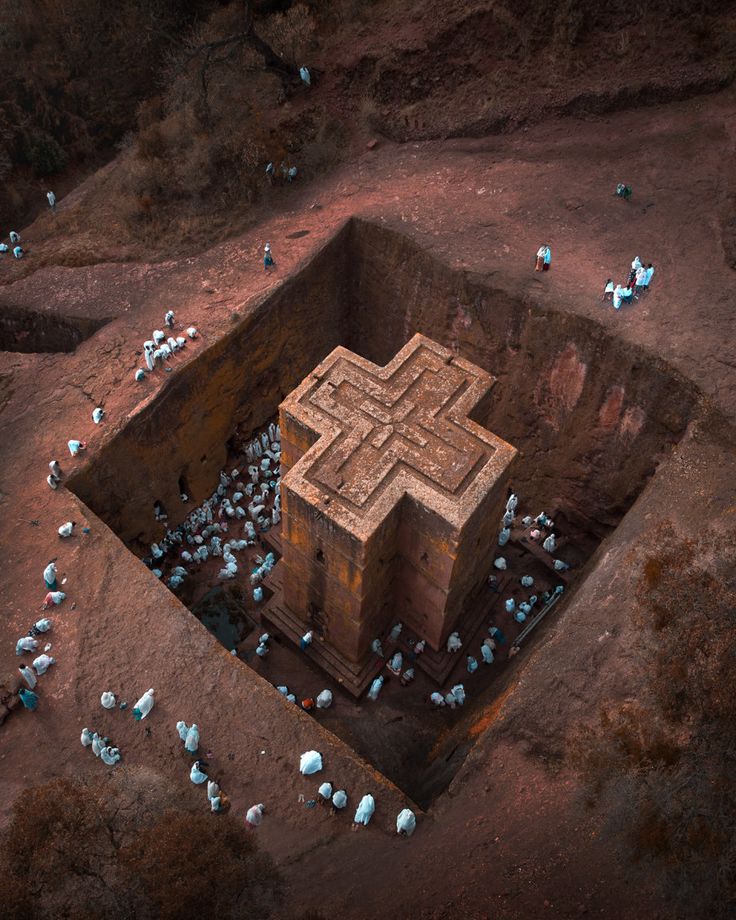 an aerial view of a building in the middle of some dirt and rocks with birds around it