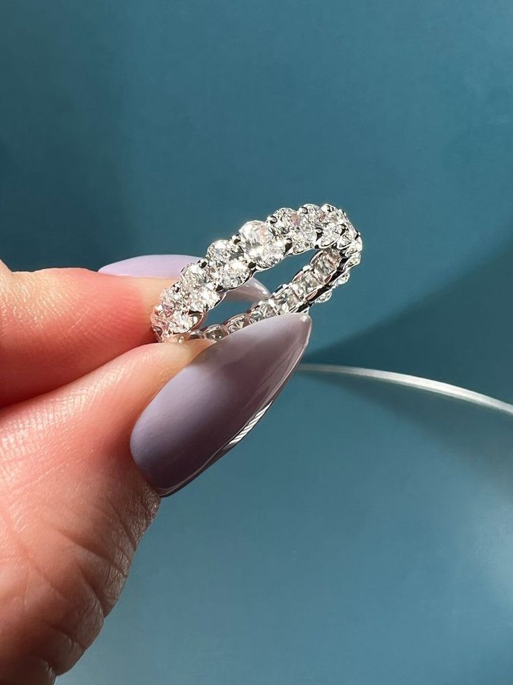 a woman's hand holding a diamond ring in front of a blue background,