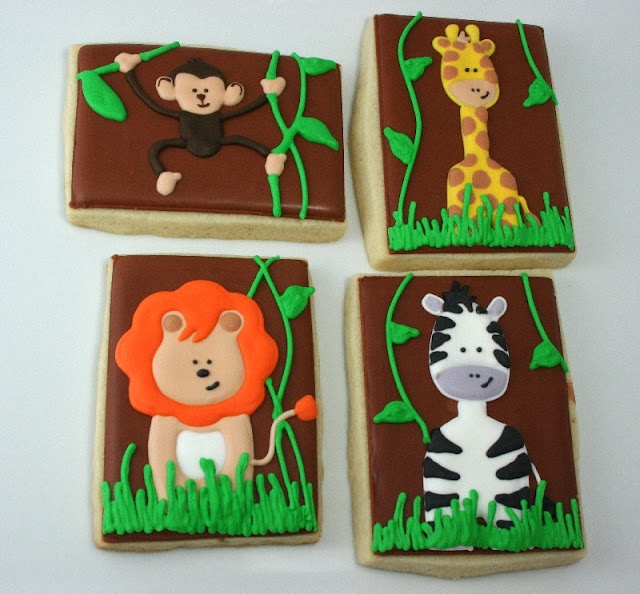 four decorated cookies in the shape of animals and giraffes