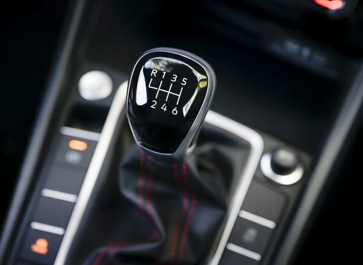 an automatic gear stick in a car with the shift button on and red stitching