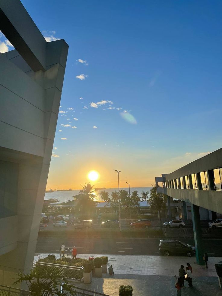 the sun is setting over some buildings and cars