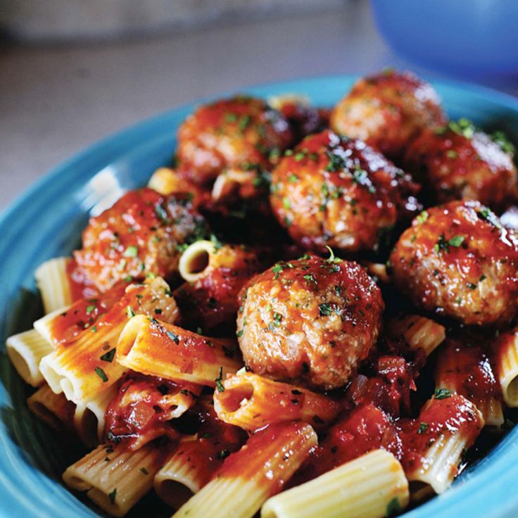 a blue bowl filled with pasta and meatballs