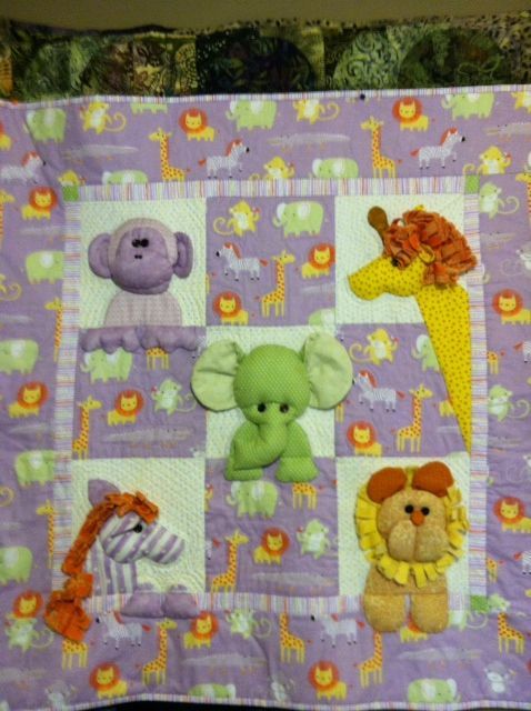 a baby quilt with stuffed animals on it's sides and purple squares around the edges