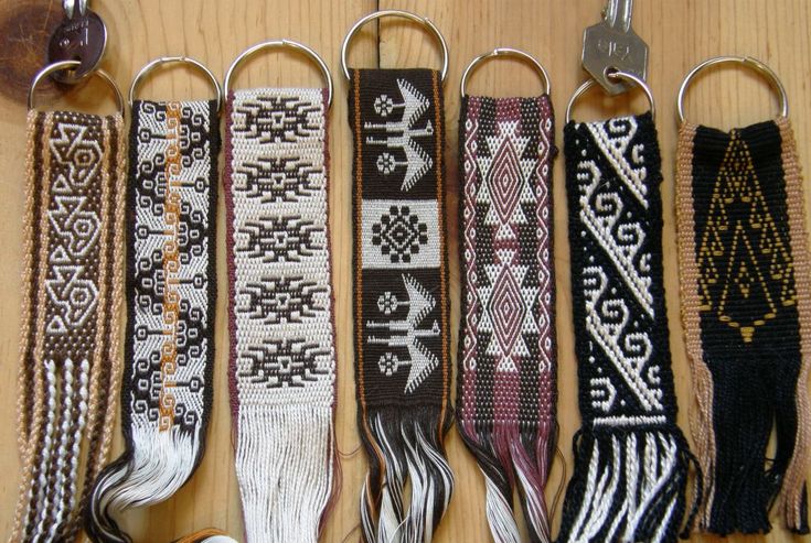 several different types of bracelets hanging from hooks on a wooden table with keys attached to them