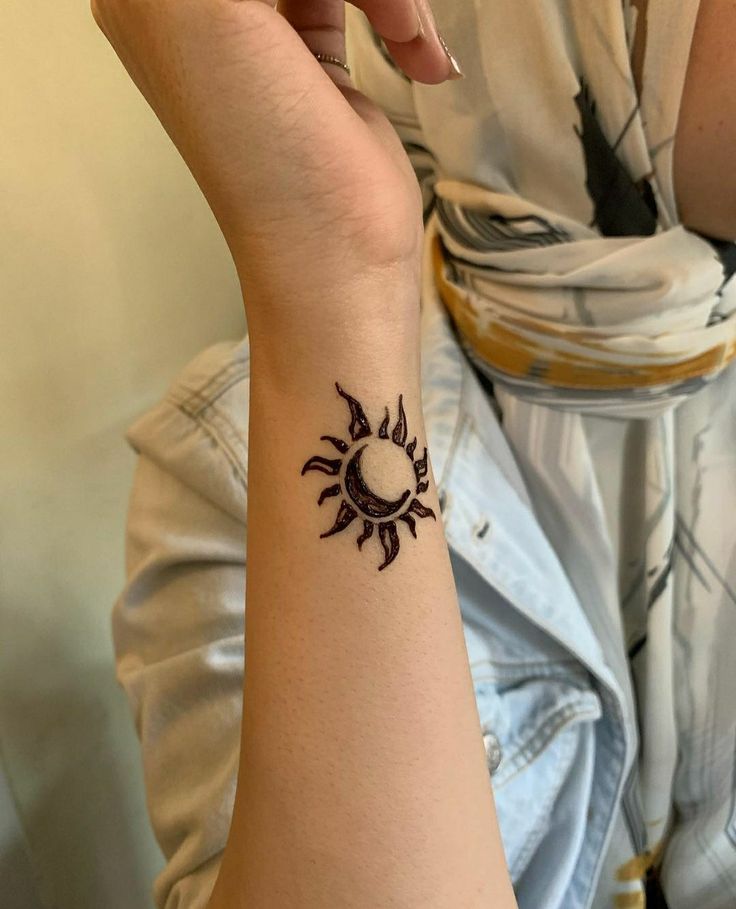 a woman's arm with a small sun tattoo on the left side of her wrist