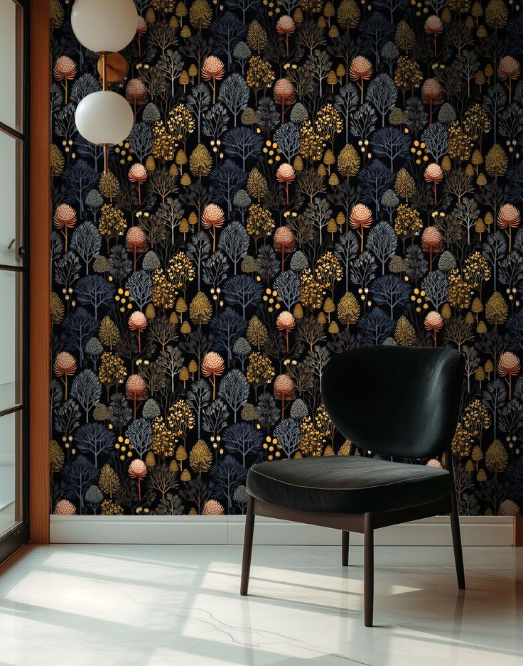 a black chair sitting in front of a wallpaper with trees and flowers on it