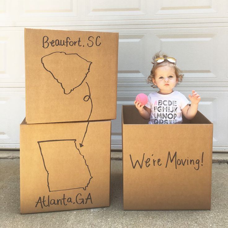 two cardboard boxes with drawings on them and a baby in the middle one holding a donut