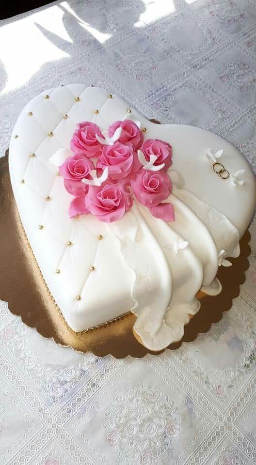 a heart shaped cake with pink roses on it sitting on top of a doily