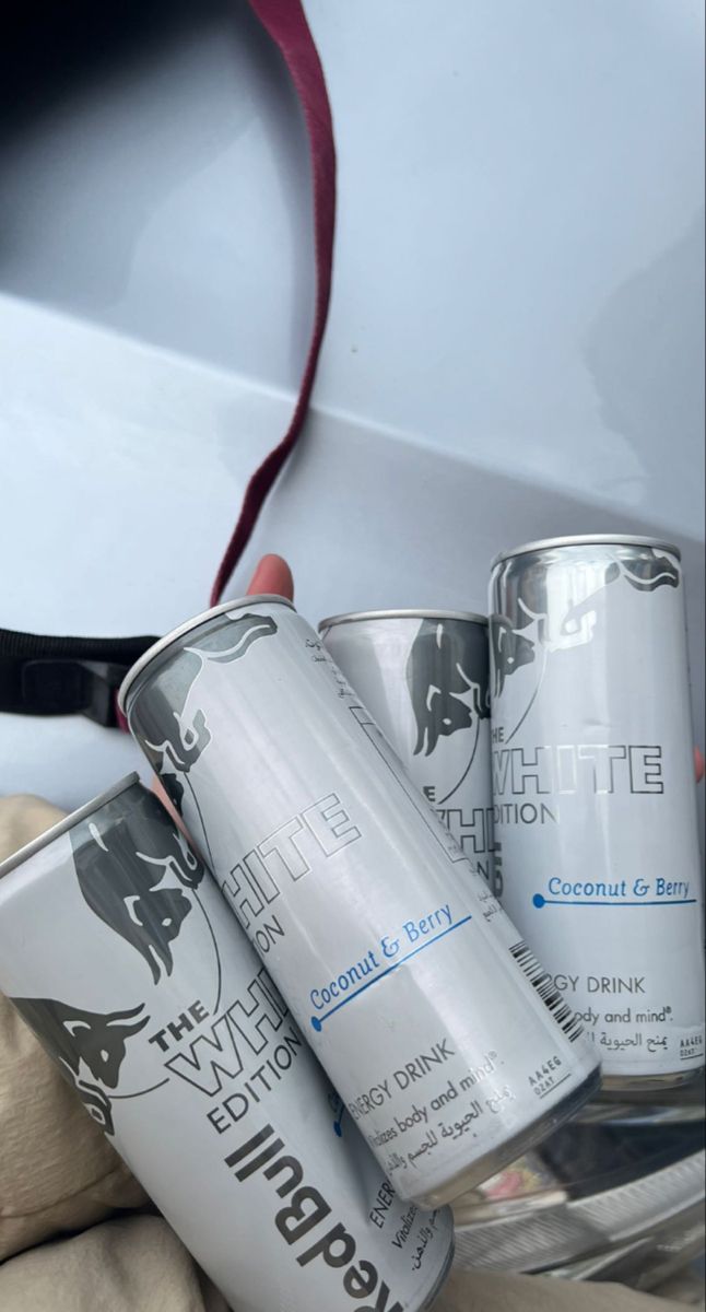 three cans of white paint sitting on top of a bed next to a red ribbon