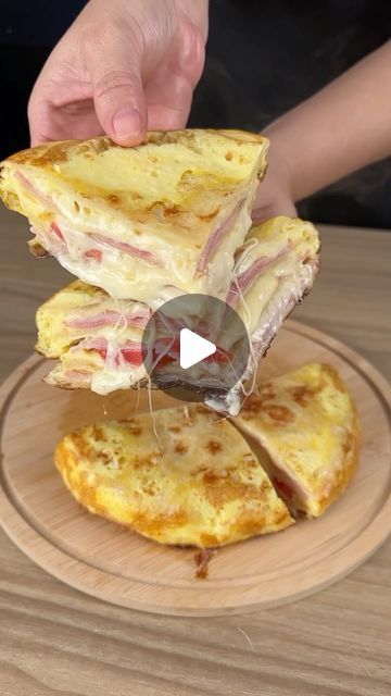 someone is cutting into a sandwich on a wooden platter with cheese and meats