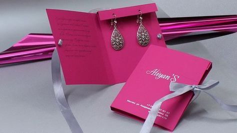 a pair of pink earrings sitting inside of a pink gift box next to a silver ribbon