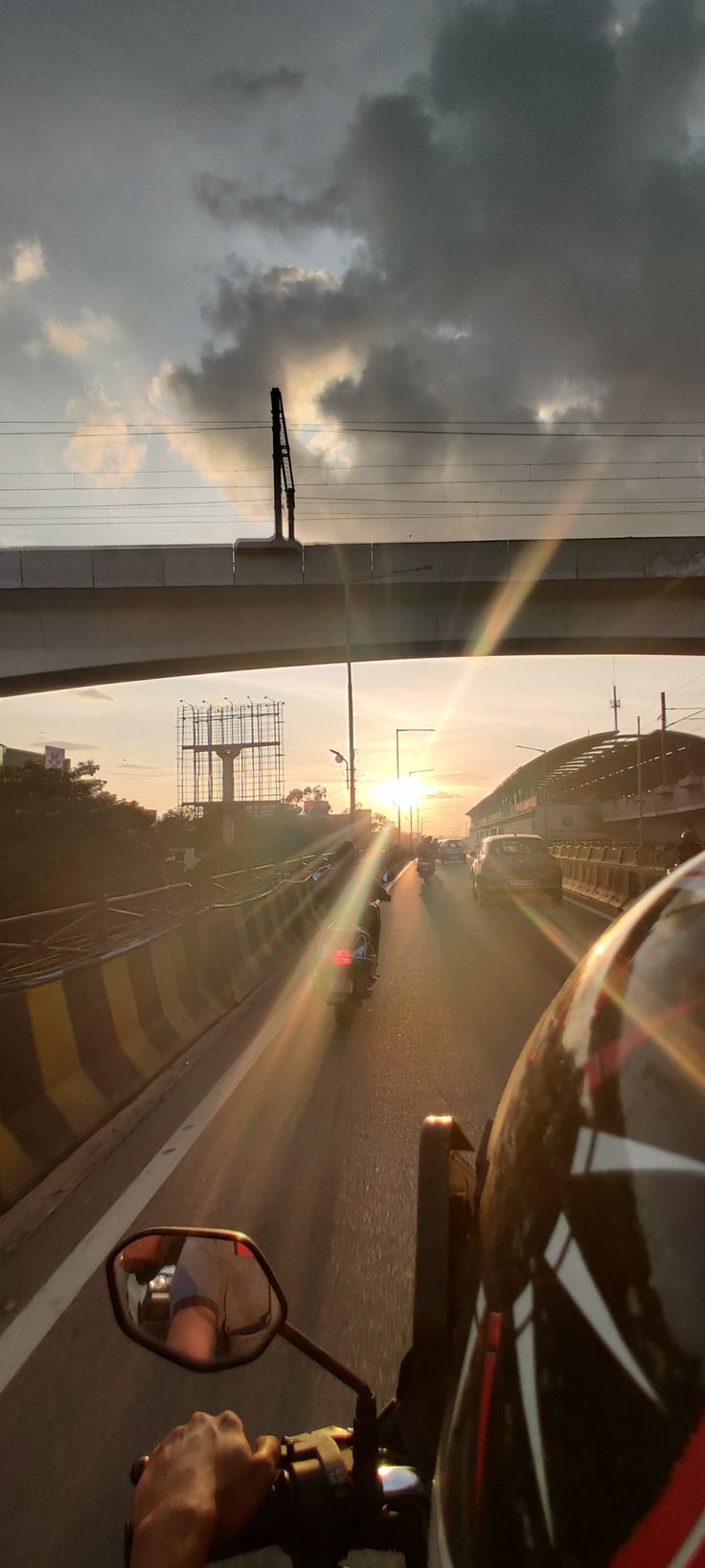 the sun is setting on an overpass and cars are driving down the road