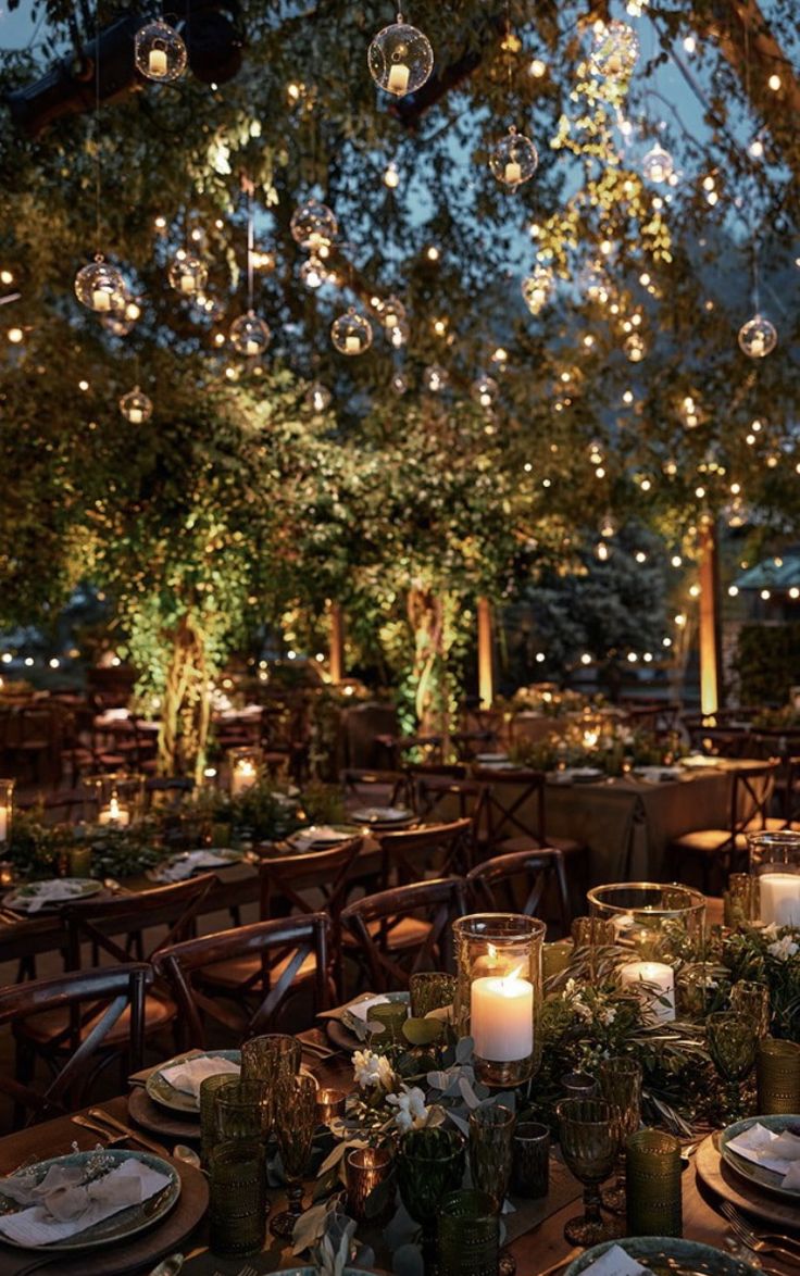 the tables are set with candles, plates and place settings for an outdoor dinner party