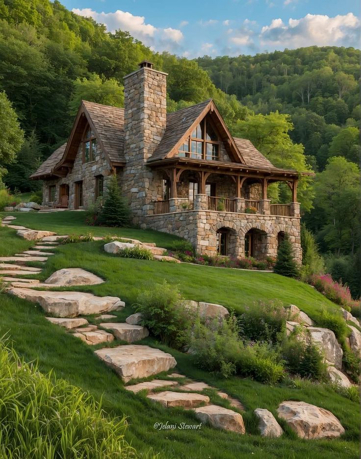 a stone house in the middle of a lush green field with rocks and trees surrounding it