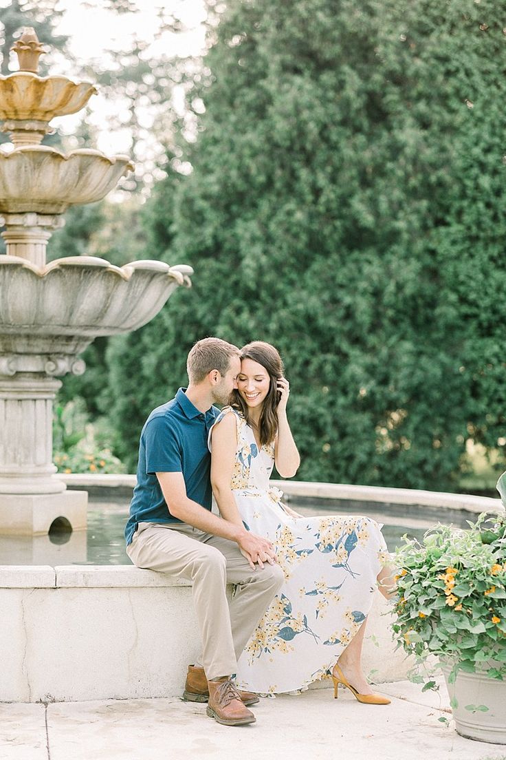 a man and woman sitting next to each other in front of a fountain